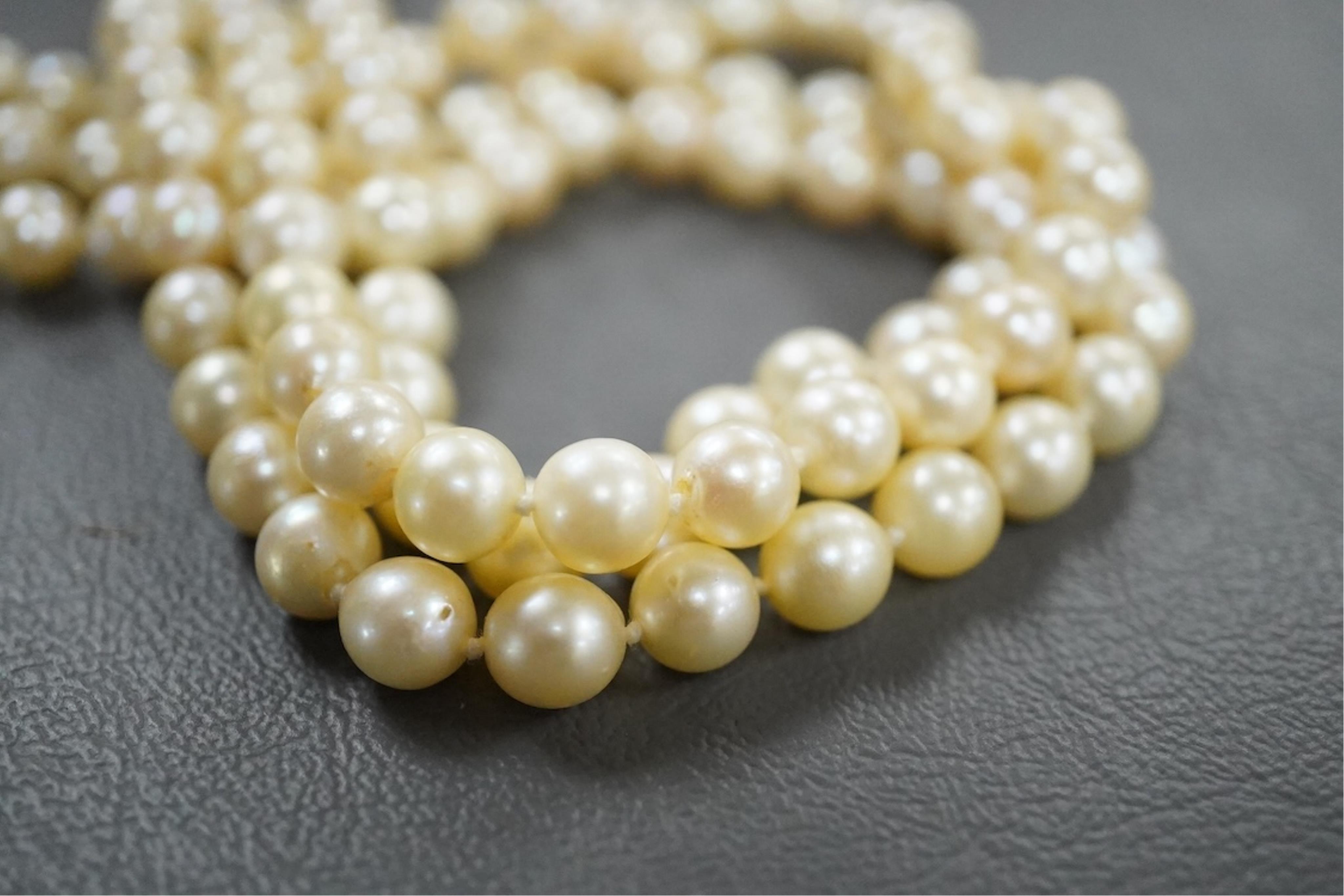 A triple strand cultured pearl necklace, with an Italian 18k white metal, ruby, sapphire and emerald set clasp, 46cm.